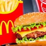 Burger, fries, and cola with red packaging.