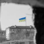 Ukraine flag on building seen through dark frame.