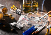 Drugs, pills, and cigarettes on a wooden table.