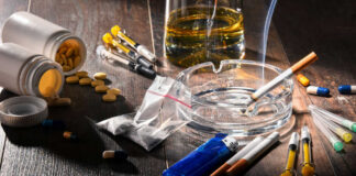 Drugs, pills, and cigarettes on a wooden table.