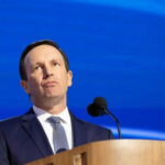 Person speaking at podium with blue background