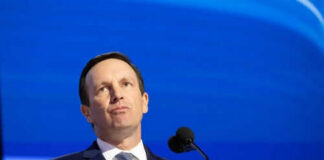 Person speaking at podium with blue background