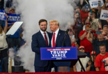 Two men at political rally with Trump Vance 2024.