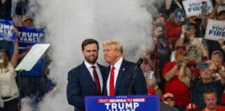 Two men at political rally with Trump Vance 2024.