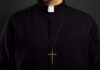 Clerical shirt with a cross necklace against a dark background