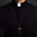 Clerical shirt with a cross necklace against a dark background