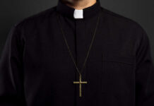 Clerical shirt with a cross necklace against a dark background