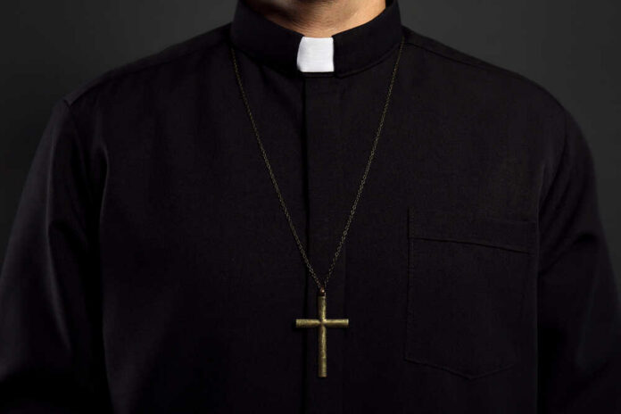 Clerical shirt with a cross necklace against a dark background