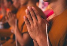 Monks with hands clasped in prayer during a ceremony