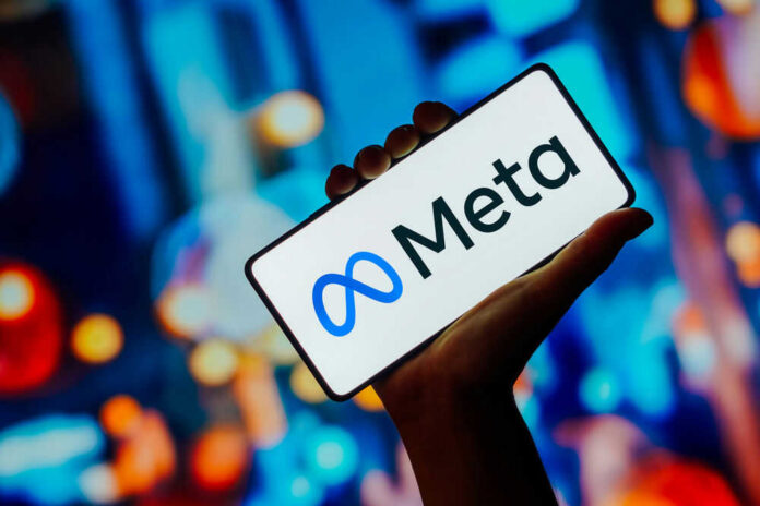 Hand holding phone displaying Meta logo.