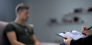 A therapist taking notes during a session with a patient in the background