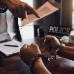 A person in handcuffs being confronted by a police officer
