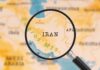 A magnifying glass focusing on the country Iran on a map