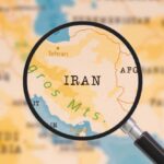 A magnifying glass focusing on the country Iran on a map