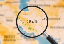 A magnifying glass focusing on the country Iran on a map