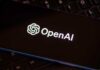 Close-up of a smartphone displaying the OpenAI logo on a dark screen