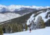 A skier navigating down a snowy slope with mountains in the background