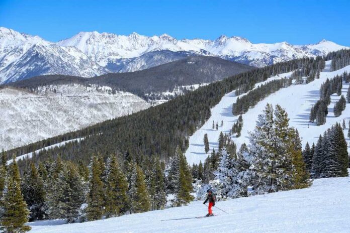 A skier navigating down a snowy slope with mountains in the background