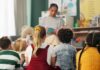 A teacher reading to a group of children sitting on the floor
