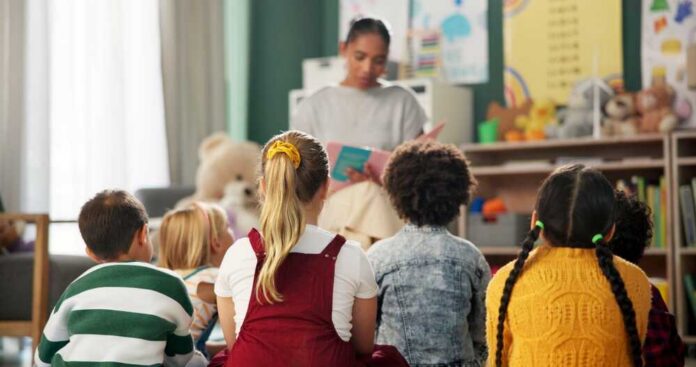 A teacher reading to a group of children sitting on the floor