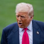 A political figure speaking outdoors with an expressive gesture