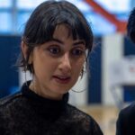 Two individuals engaged in a conversation indoors, with one showing a focused expression