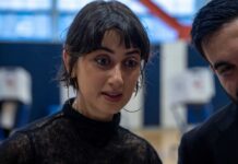 Two individuals engaged in a conversation indoors, with one showing a focused expression