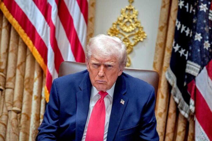 Donald Trump seated in the Oval Office with a serious expression