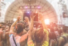 Crowd at a music festival with hands raised in celebration