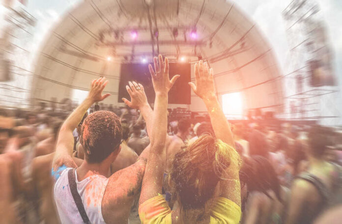 Crowd at a music festival with hands raised in celebration