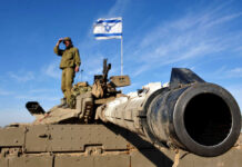 Soldier saluting from atop a tank with an Israeli flag in the background