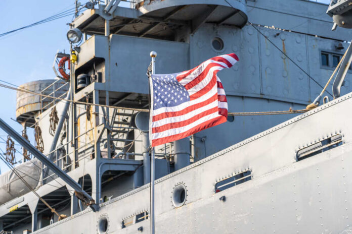 American flag waving in front of a naval ship
