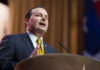 A man in a suit delivering a speech at a podium