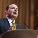 A man in a suit delivering a speech at a podium
