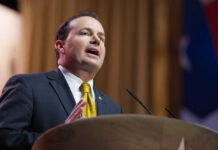 A man in a suit delivering a speech at a podium