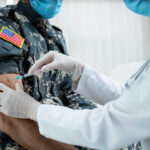 A healthcare professional administering a vaccine to a soldier