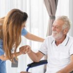 Healthcare worker assisting a smiling elderly man in a wheelchair