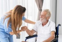Healthcare worker assisting a smiling elderly man in a wheelchair