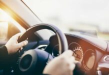 Hands gripping a steering wheel inside a car