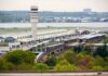 Aerial view of an airport terminal with a control tower and surrounding greenery