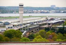 Aerial view of an airport terminal with a control tower and surrounding greenery