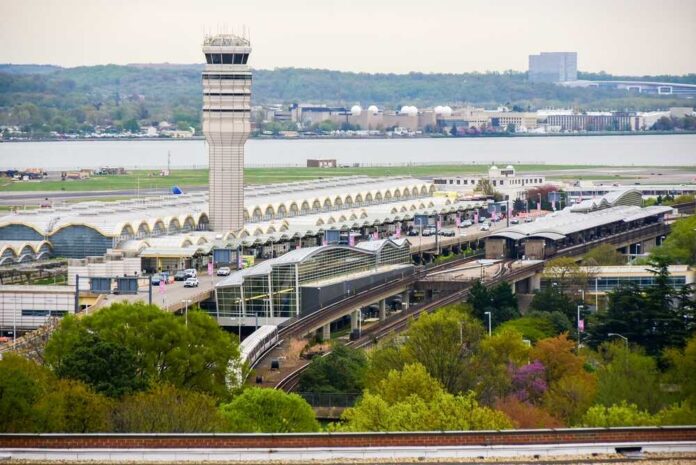 Aerial view of an airport terminal with a control tower and surrounding greenery
