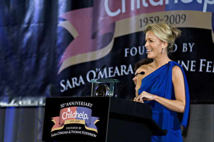 A woman in a blue dress speaking at a charity event podium