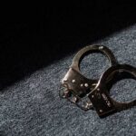 A pair of handcuffs resting on a dark surface with light casting a shadow
