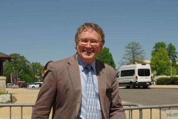 A smiling man in a suit standing outdoors on a sunny day