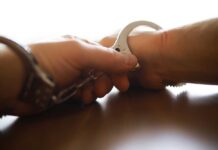 Close-up of a handcuff being secured on a wrist