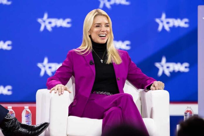 A woman in a bright pink suit smiling while seated on a stage