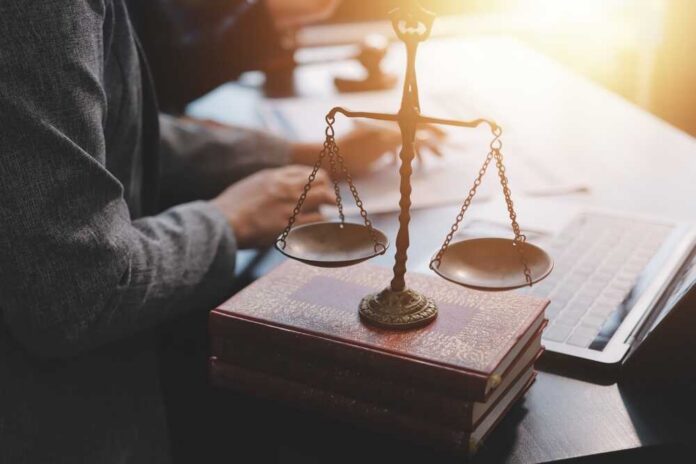 A set of legal scales on top of law books with a person working in the background