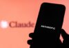 A hand holding a smartphone displaying the word 'ANTHROPIC' against a blurred background