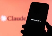 A hand holding a smartphone displaying the word 'ANTHROPIC' against a blurred background